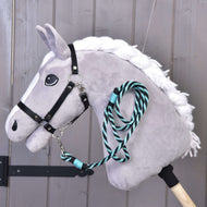 Szürke Hobby Horse ló fonott fehér sörénnyel és fekete kötőfékkel, az álla alá csatolt zöld csíkos vezetőszárral