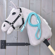 Világosszürke Hobby Horse ló fekete kötőfékben, a nyakára vetve a türkiz Atlantis csíkos vezetőszár