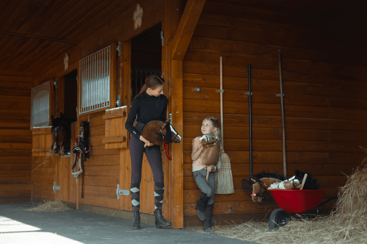 Fiatalok Hobby Horse lovakkal egy lovasklub faistállói előtt