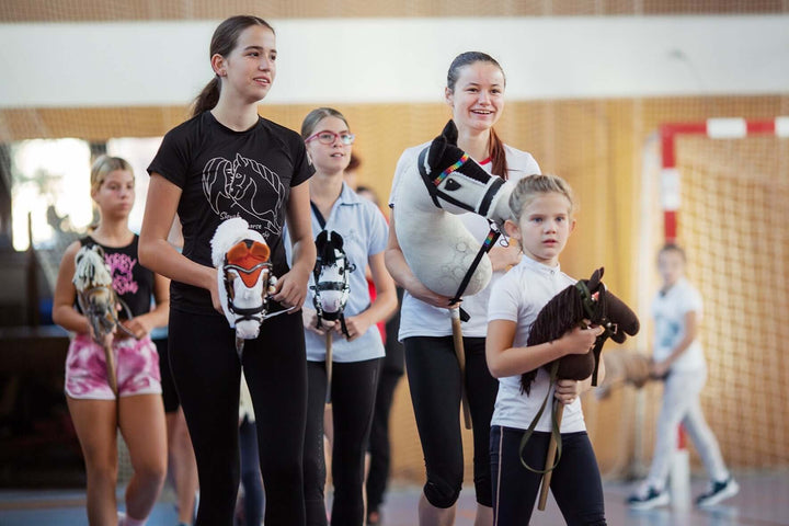 Gyerekek és tinédzserek Hobby Horse lovakkal egy fedett Hobby Horsing eseményen