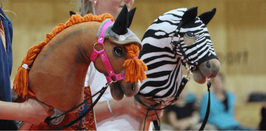 Két Hobby Horse ló befont sörénnyel: az egyik barna, narancssárga fonallal, a másik zebramintás
