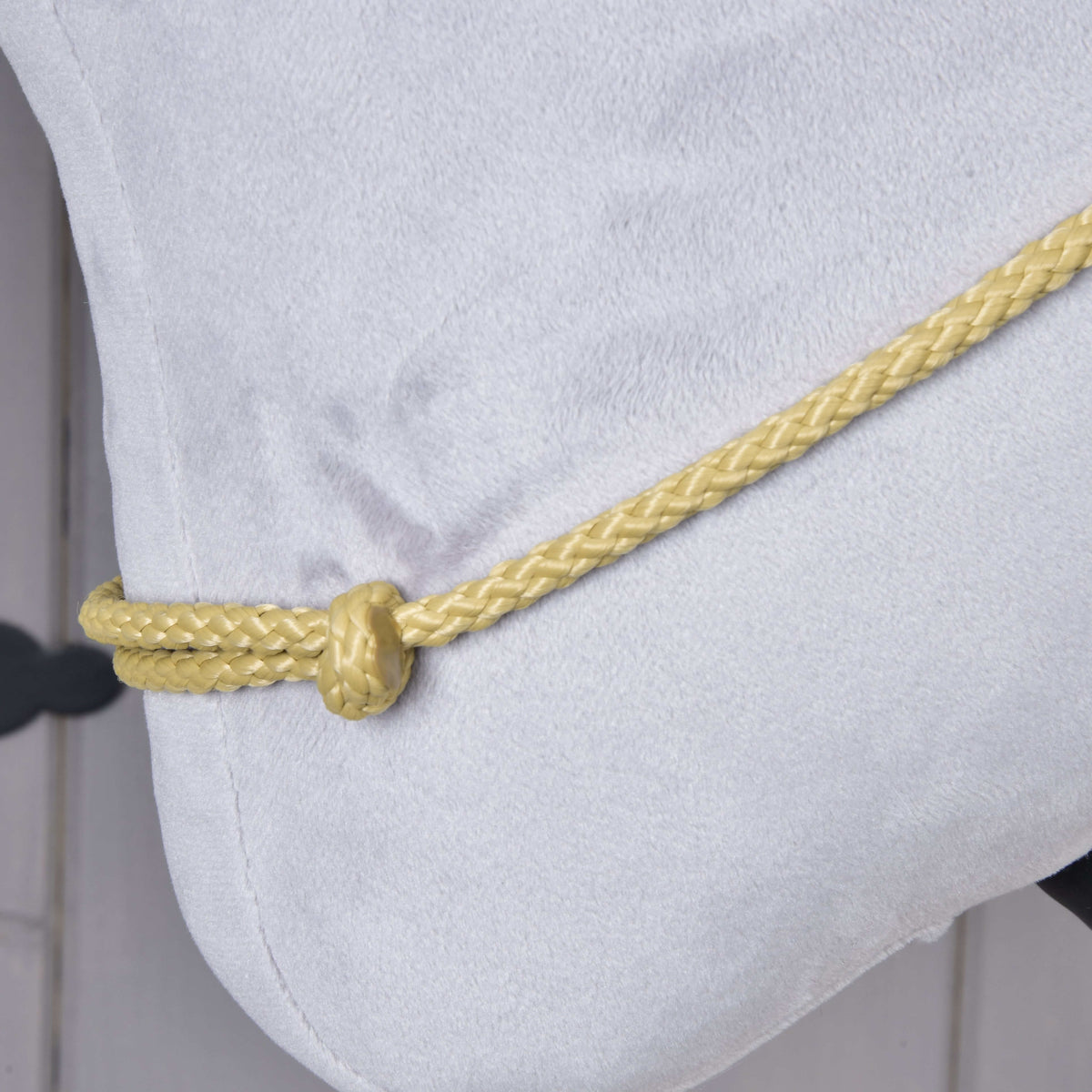 Close-up of the Hobby Horse Cordeo Nature: braided sand-coloured cord and its knot resting on grey plush