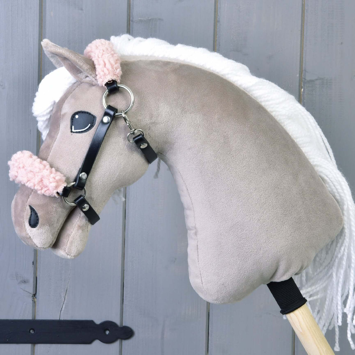 A beige plush Hobby Horse with a white mane wears the black halter with curly old rose fur on noseband and crownpiece