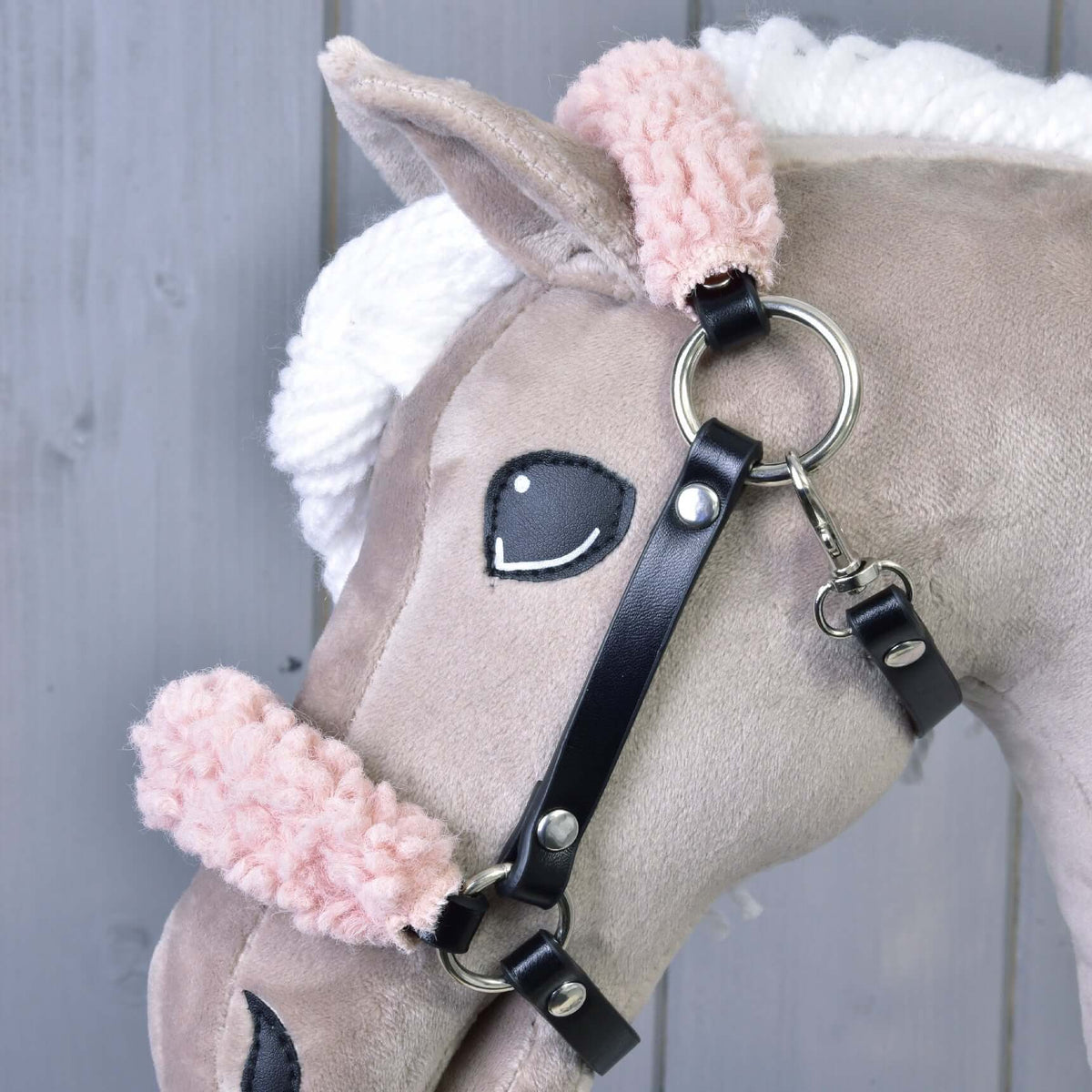 Close-up of the black leatherette halter on a beige Hobby Horse, showing the curly pink fur, silver ring and snap hook