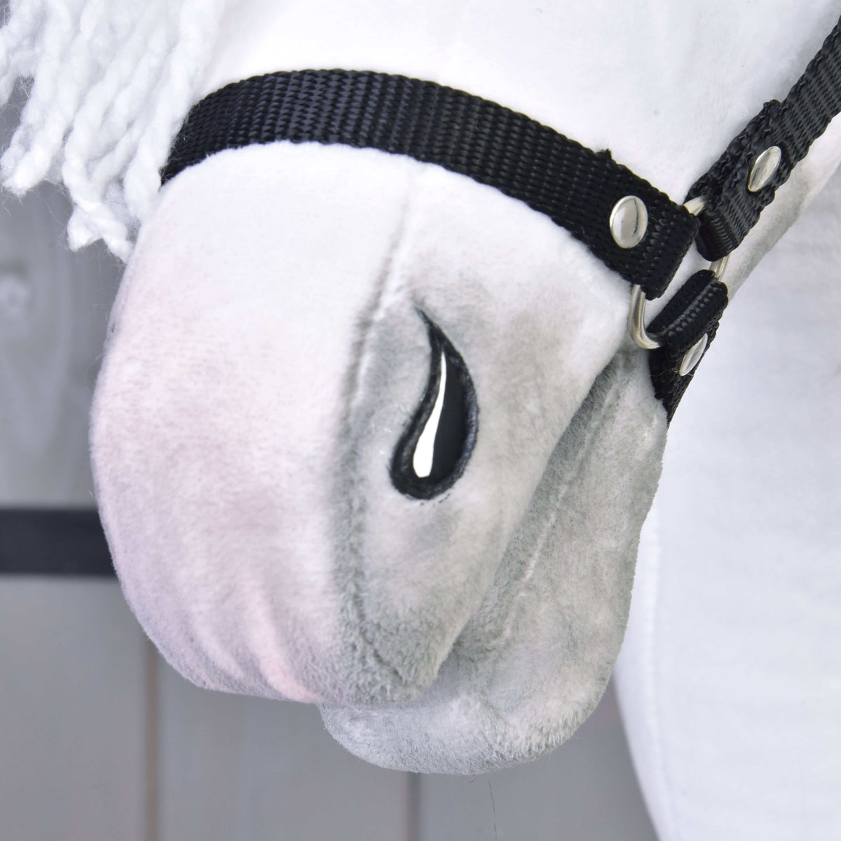 Közeli kép a Hobby Horse Elektra ló finoman szürkén árnyalt orráról, hímzett fekete orrlyukáról és a fekete kötőfék orrszíjáról
