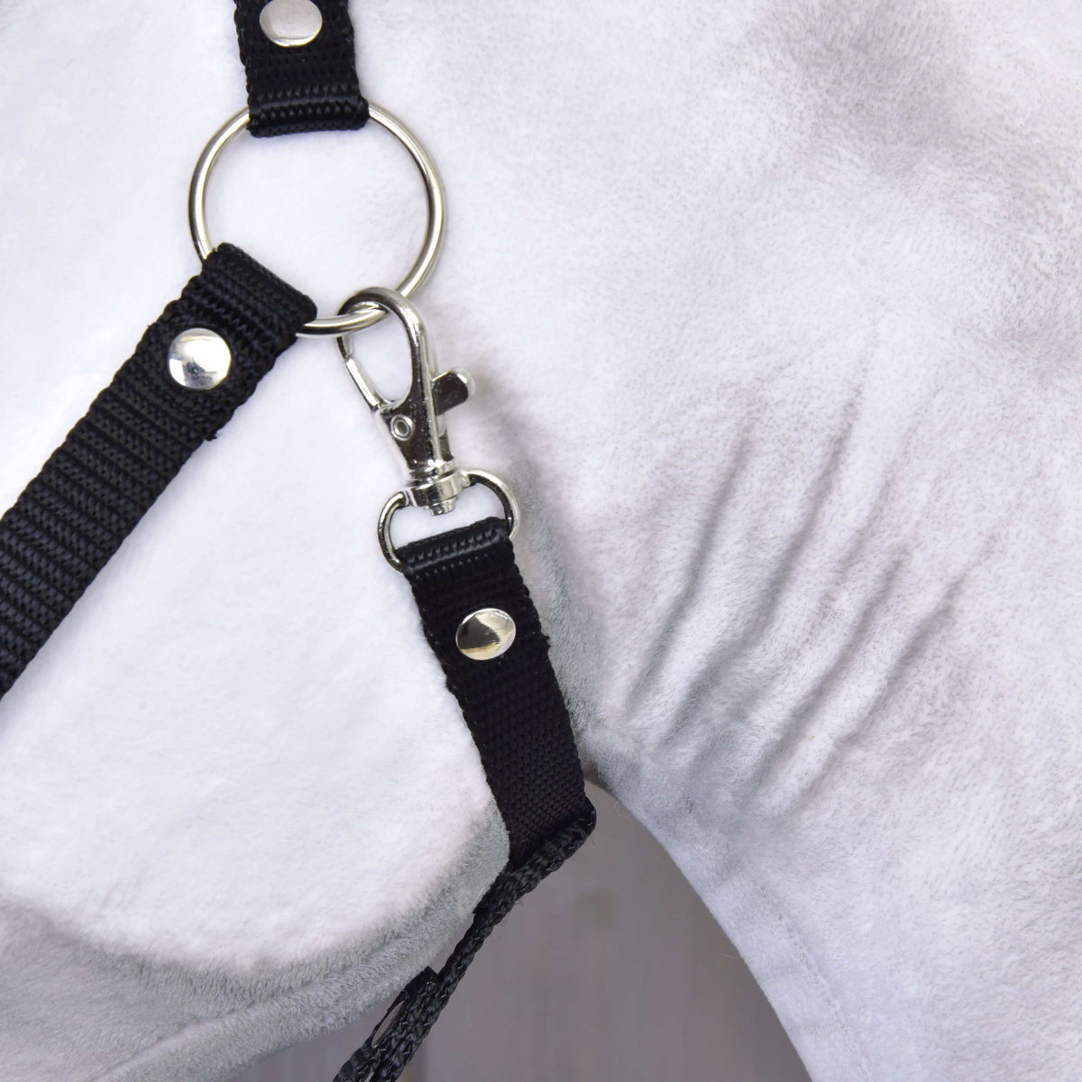 Közeli kép a fekete kötőfék ezüst karikájáról és karabineréről a Hobby Horse Elektra ló fehér plüsspofáján