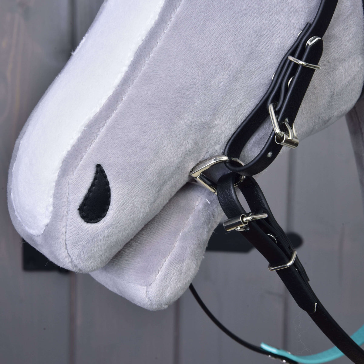 Közeli kép egy szürke Hobby Horse ló orráról fekete pofaszíjakkal, csatokkal és zablakarikával, orrszíj nélkül