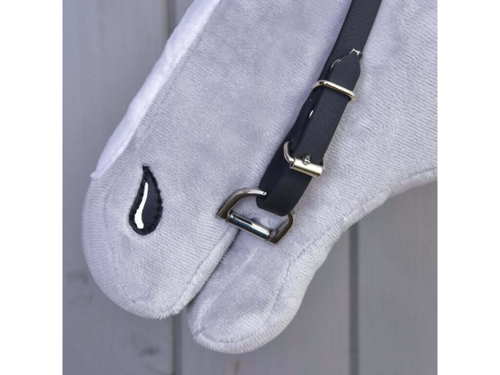 Close-up of the silver bit ring and buckle of the black bridle at the muzzle of a grey Hobby Horse