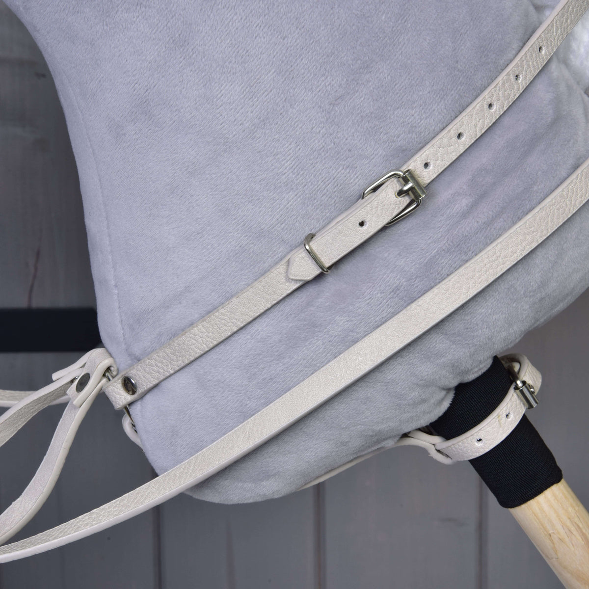Close-up of the cream martingale neck strap with buckle and the reins on the neck of a grey Hobby Horse
