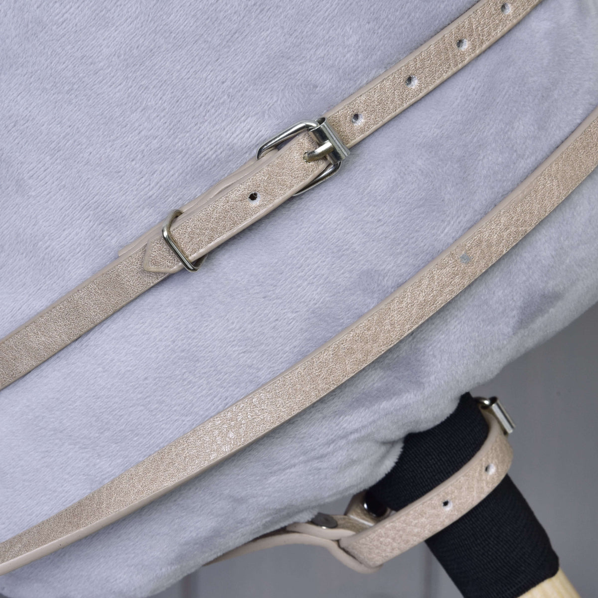 Close-up of the beige martingale neck strap with buckle and the reins on the neck of a grey Hobby Horse