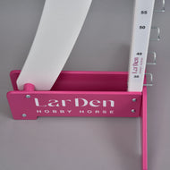 Közeli kép egy fehér LarDen Hobby Horse feliratos rózsaszín talpról, amely a 30-tól 55 cm-ig jelölt oszlopot tartja