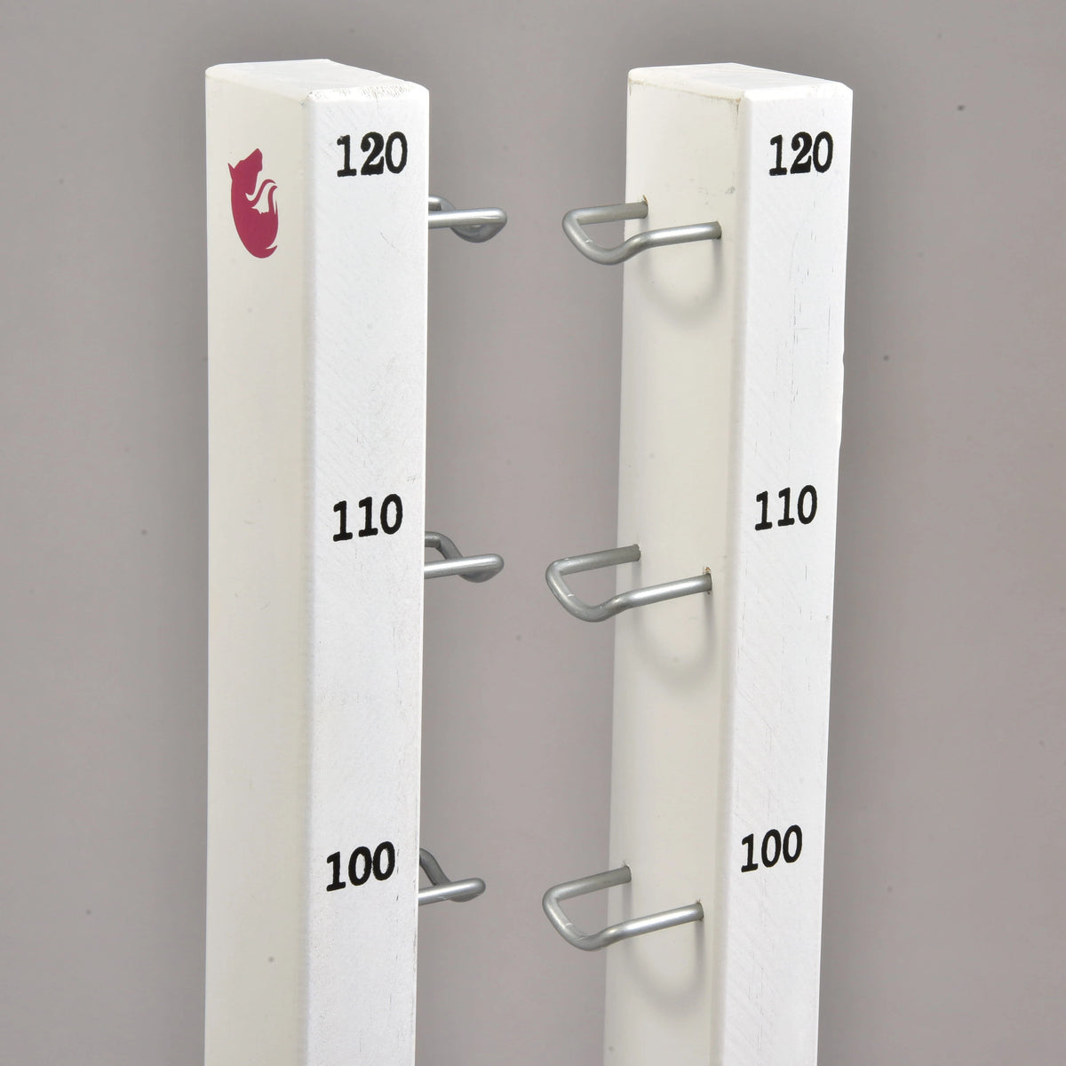 A két magas oszlop teteje 100, 110 és 120 cm-es jelzésekkel, fém tartókampókkal és kis rózsaszín lólogóval