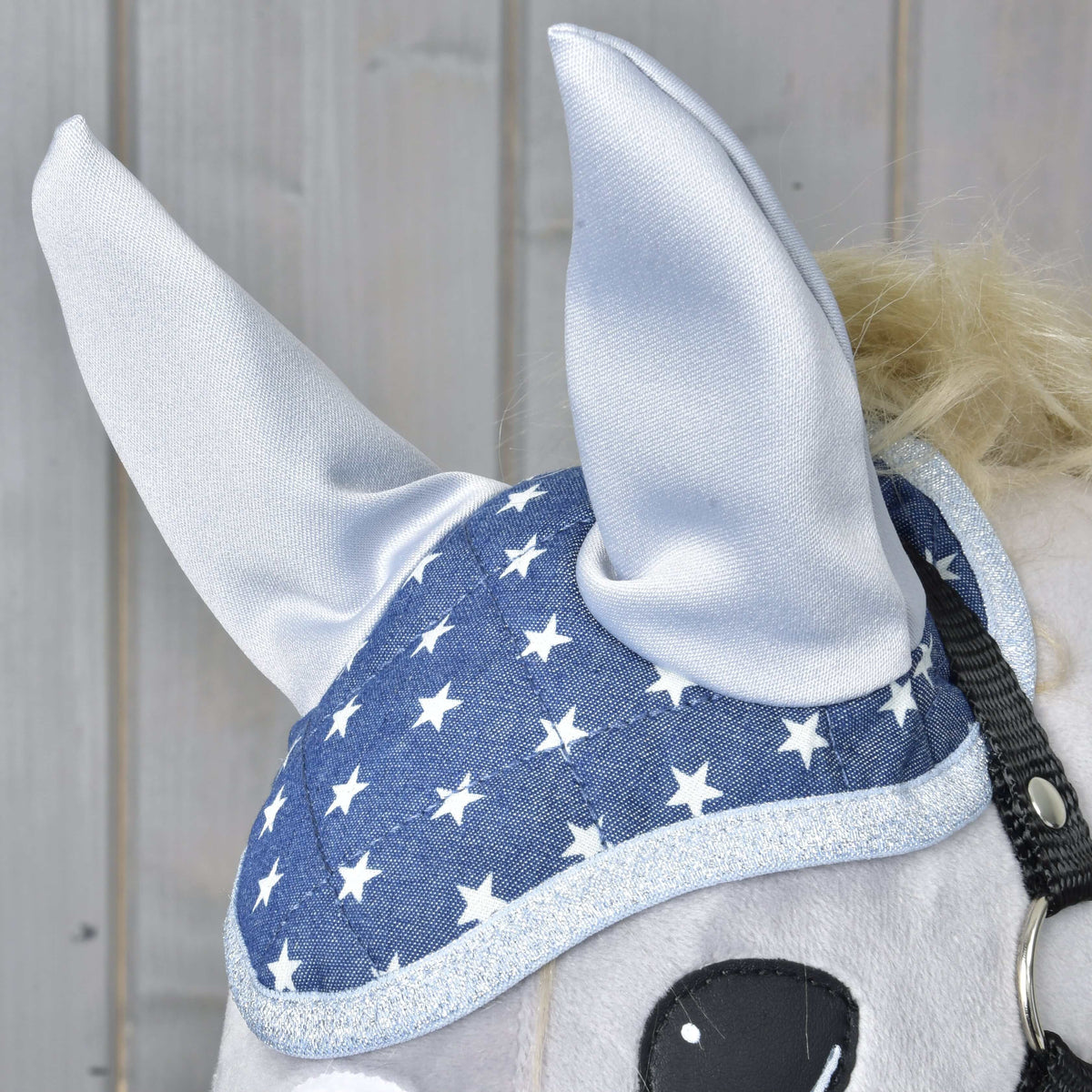A Star fülvédő közelről egy szürke Hobby Horse lovon: ezüst szaténfülek, csillagminta és csillogó ezüst szegély