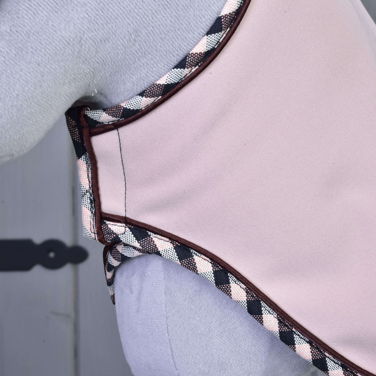 Close-up of the pale pink Set Abby blanket at the chest of a grey Hobby Horse, with checked binding and fine brown piping