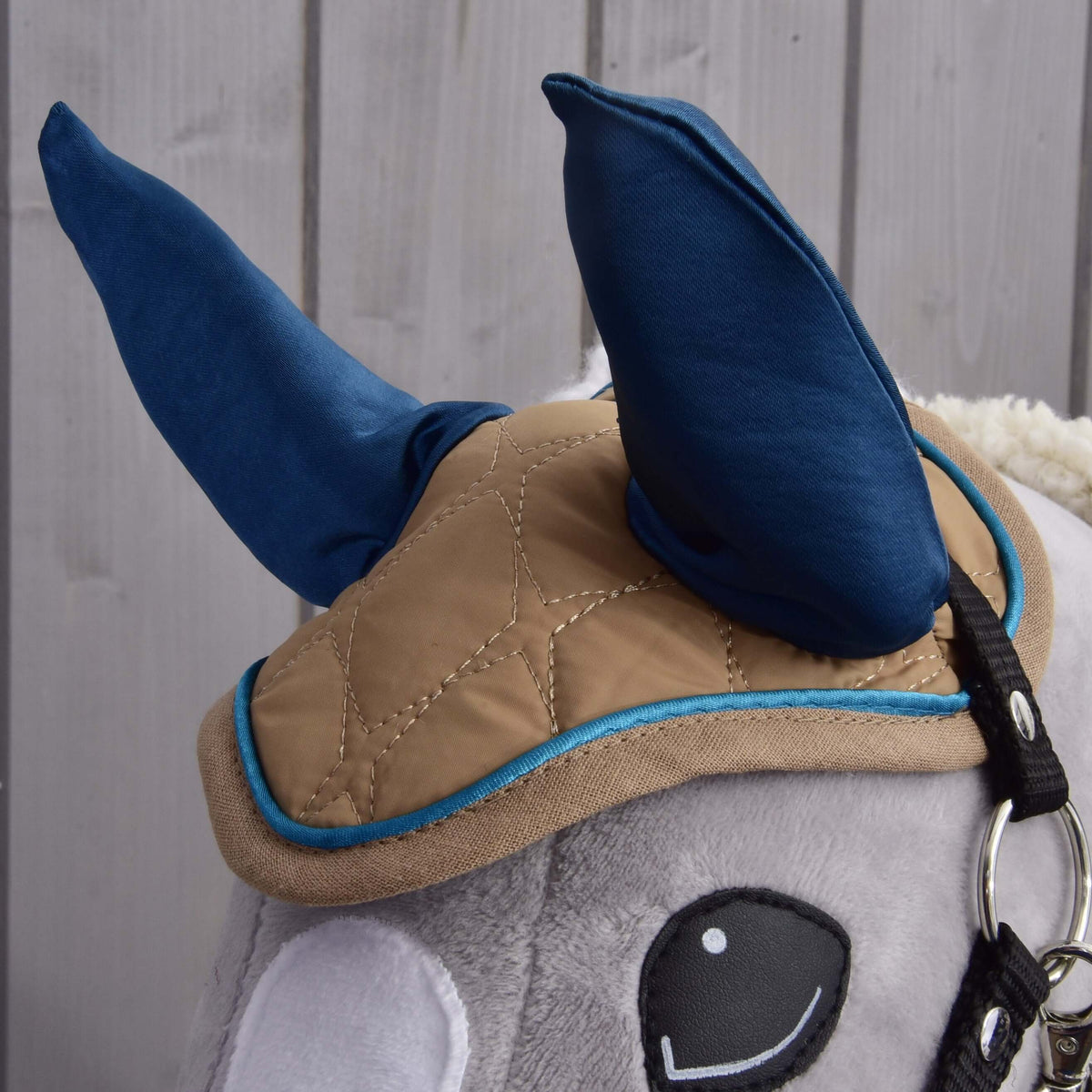 Close-up of the Almond Star ear bonnet with tall navy ears, beige diamond quilting and blue piping on a grey head