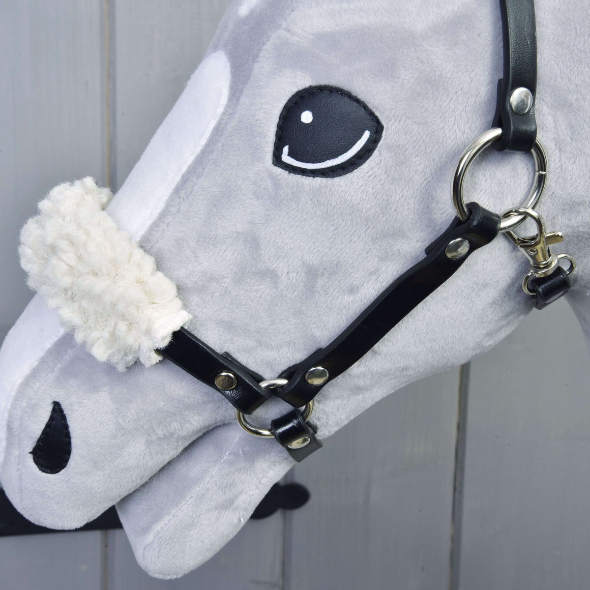 Close-up of the Set Basic halter on a Hobby Horse: black straps, silver rings and a fluffy cream fleece noseband