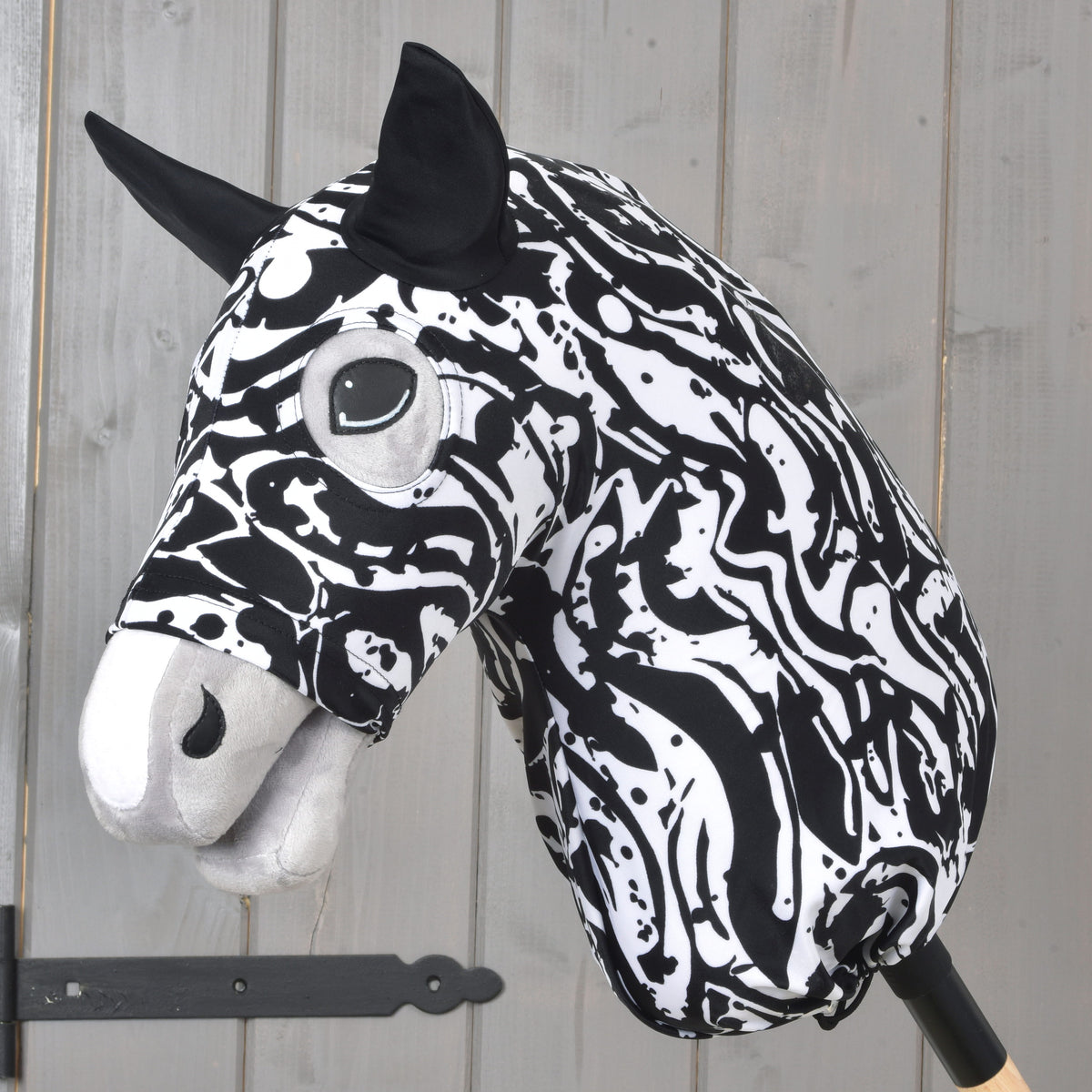 Hobby Horse védőruha Black & White a LarDen kollekciójából, örvénylő fekete-fehér mintával és fekete fülekkel, egy szürke plüssfejen