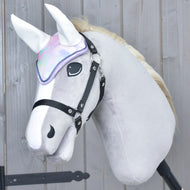 Light grey Hobby Horse wearing the pastel ear bonnet with white ears and a black halter against a wooden wall