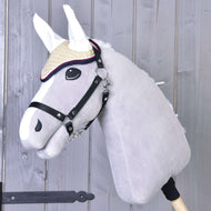Szürke Hobby Horse ló fekete kötőfékben, a krémszínű horgolt Nicol fülvédőben fehér fülrészekkel és piros-sötétkék szegéllyel