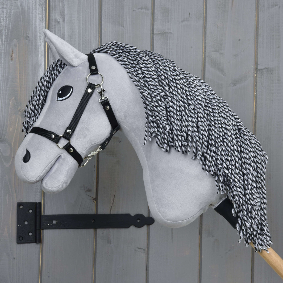 Hobby Horse Caesar in left profile with the long twisted black and white yarn mane over the light grey neck