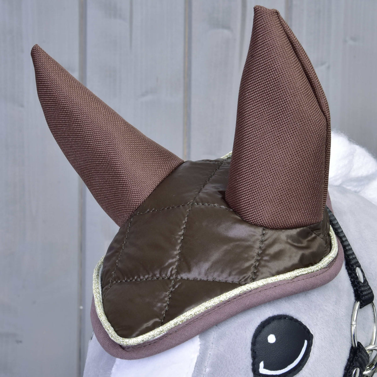 Közeli kép a Hobby Horse Thermo Chocolate szett fülvédőjéről: steppelt barna felső rész, barna textilfülek és aranyszegélyes díszítés