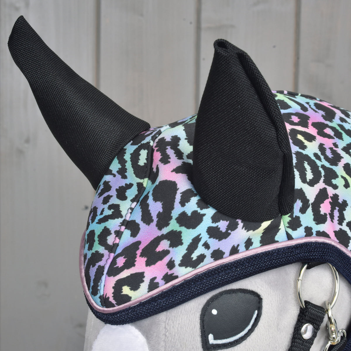 Close-up of the black ears on the Raincoat Confetti hood, pastel leopard print and navy binding with pink piping above the eye