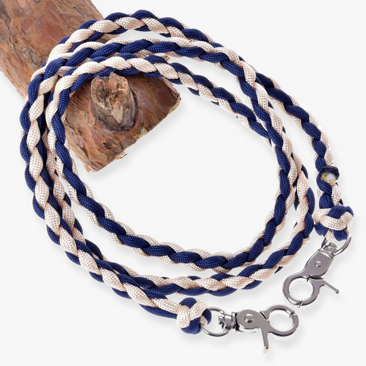 Hobby Horse Reins Cremo/Blue by LarDen, braided navy blue and cream cord with two silver snap hooks, on a branch