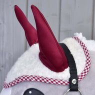 A fehér sherpa fülvédő bordó fülei és piros kockás szegélye egy szürke Hobby Horse lovon, látszik a fekete kötőfék szíja