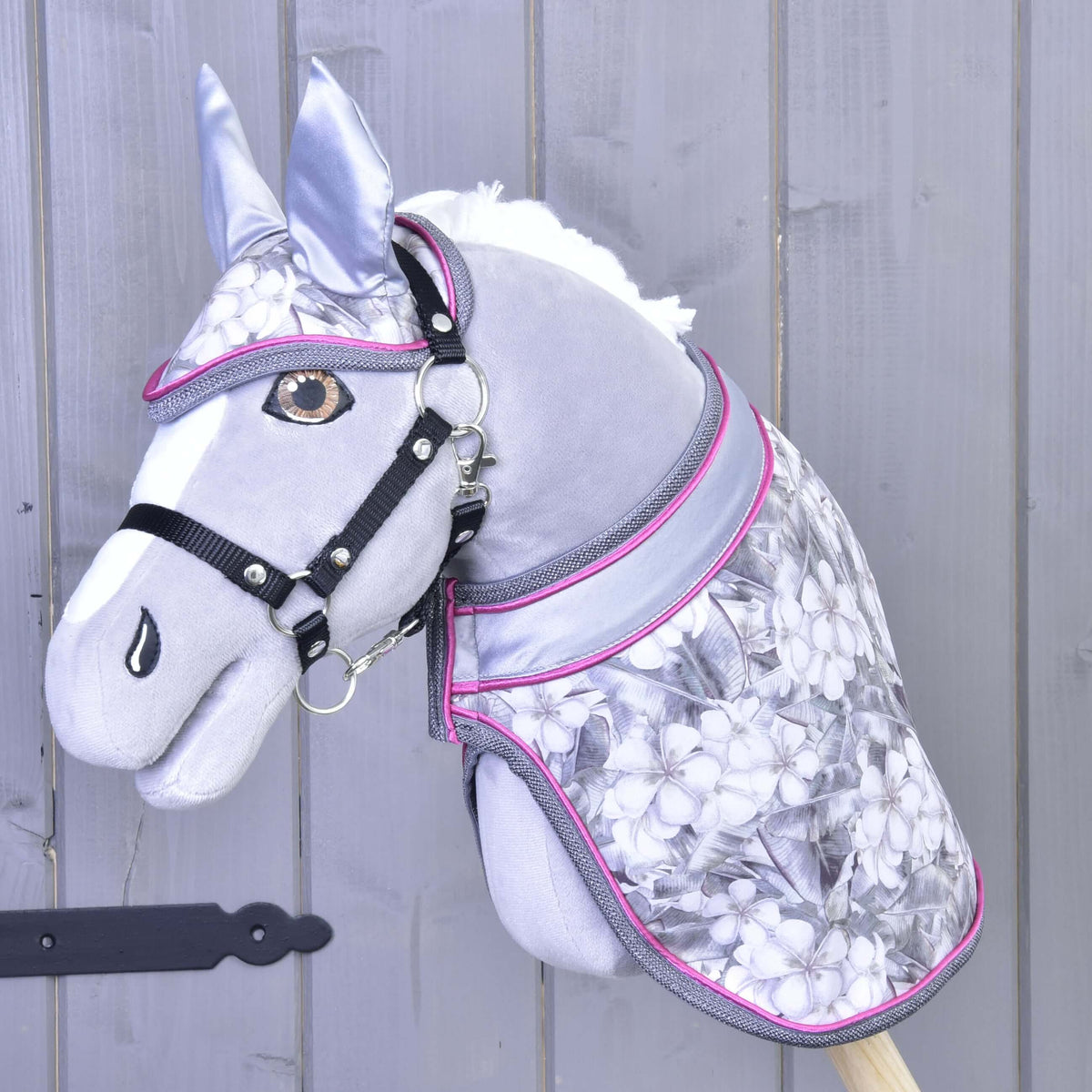 Grey Hobby Horse with amber eyes and black halter wearing Set Grey Flower, the floral blanket and ear bonnet with pink trim