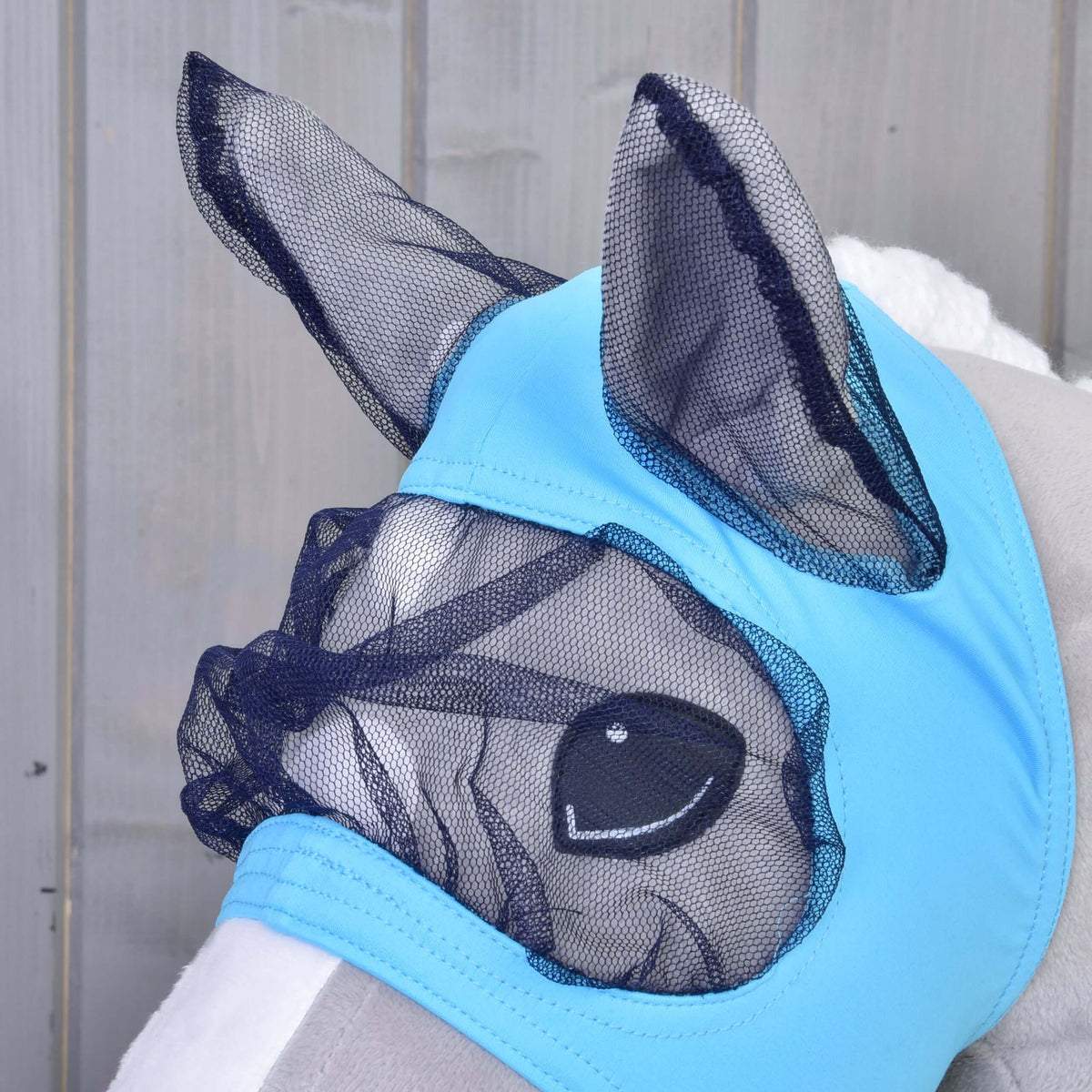 Close-up of the Hobby Horse Fly Mask on a grey head: navy mesh ears and eye net set into light blue fabric