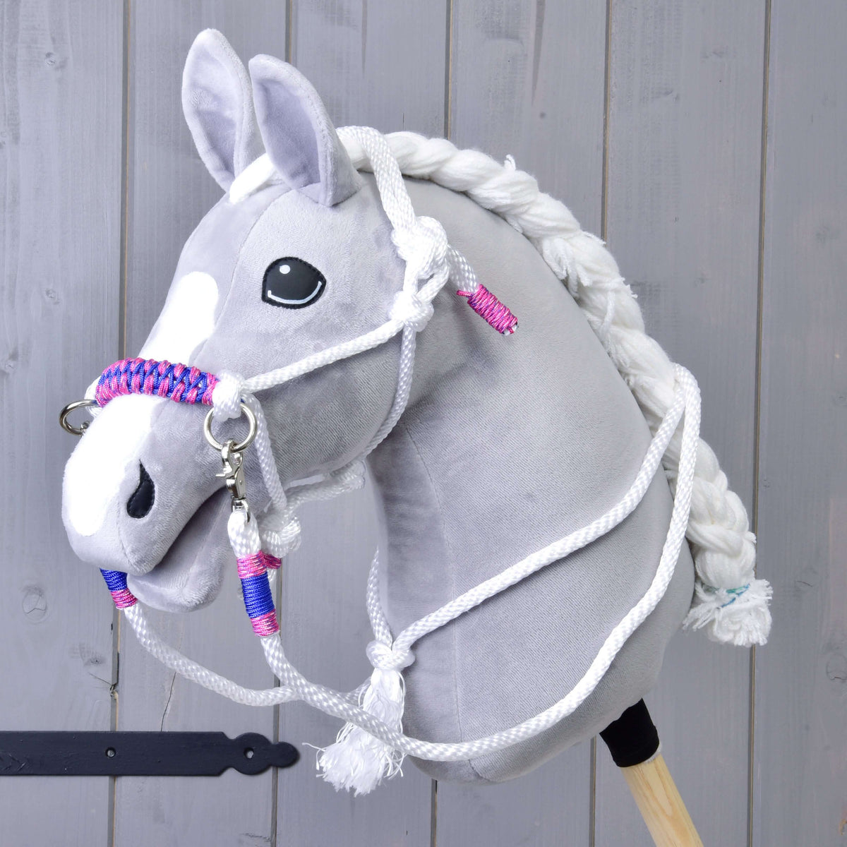 Grey plush Hobby Horse wearing the white rope halter with pink and blue braided noseband and matching white reins