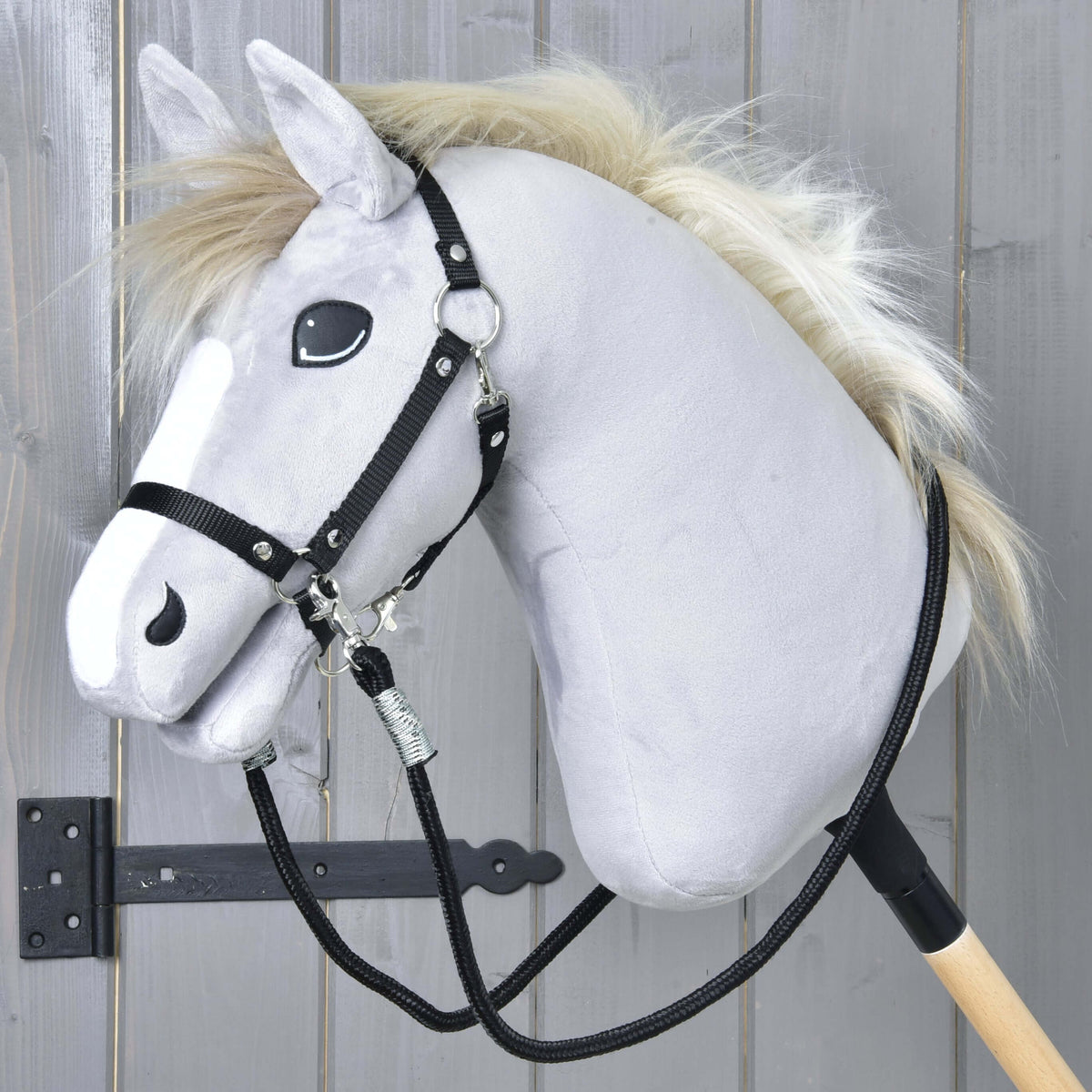 Grey Hobby Horse with a blond mane and black halter, the black braided reins clipped to both sides and hanging loose