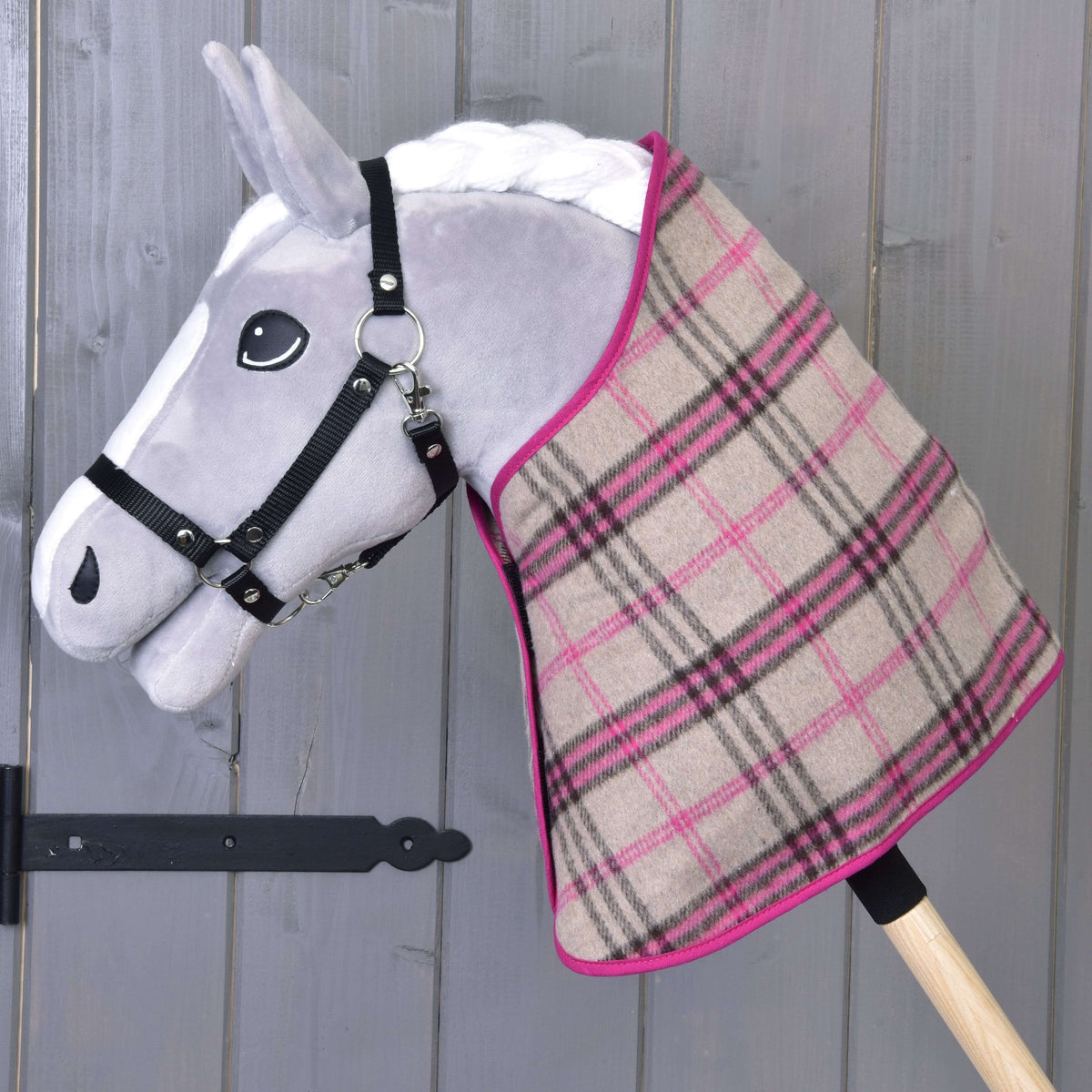 Szürke Hobby Horse ló fekete kötőfékben, rajta csak a bézs-rózsaszín kockás takaró rózsaszín szegéssel