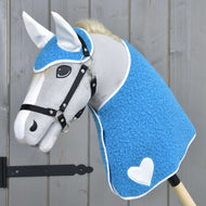 Szürke plüss Hobby Horse ló fekete kötőfékben, a kék göndör takaróban és fülvédőben, fehér szívvel és fehér fülrészekkel