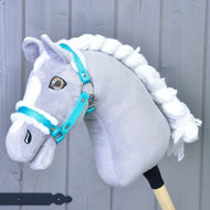 Szürke plüss Hobby Horse ló fonott fehér sörénnyel és barna szemekkel, rajta a türkiz kötőfék fehér szőrmével