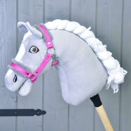Szürke plüss Hobby Horse ló fonott fehér sörénnyel és barna szemekkel, rajta az élénk rózsaszín kötőfék szürke szőrmével