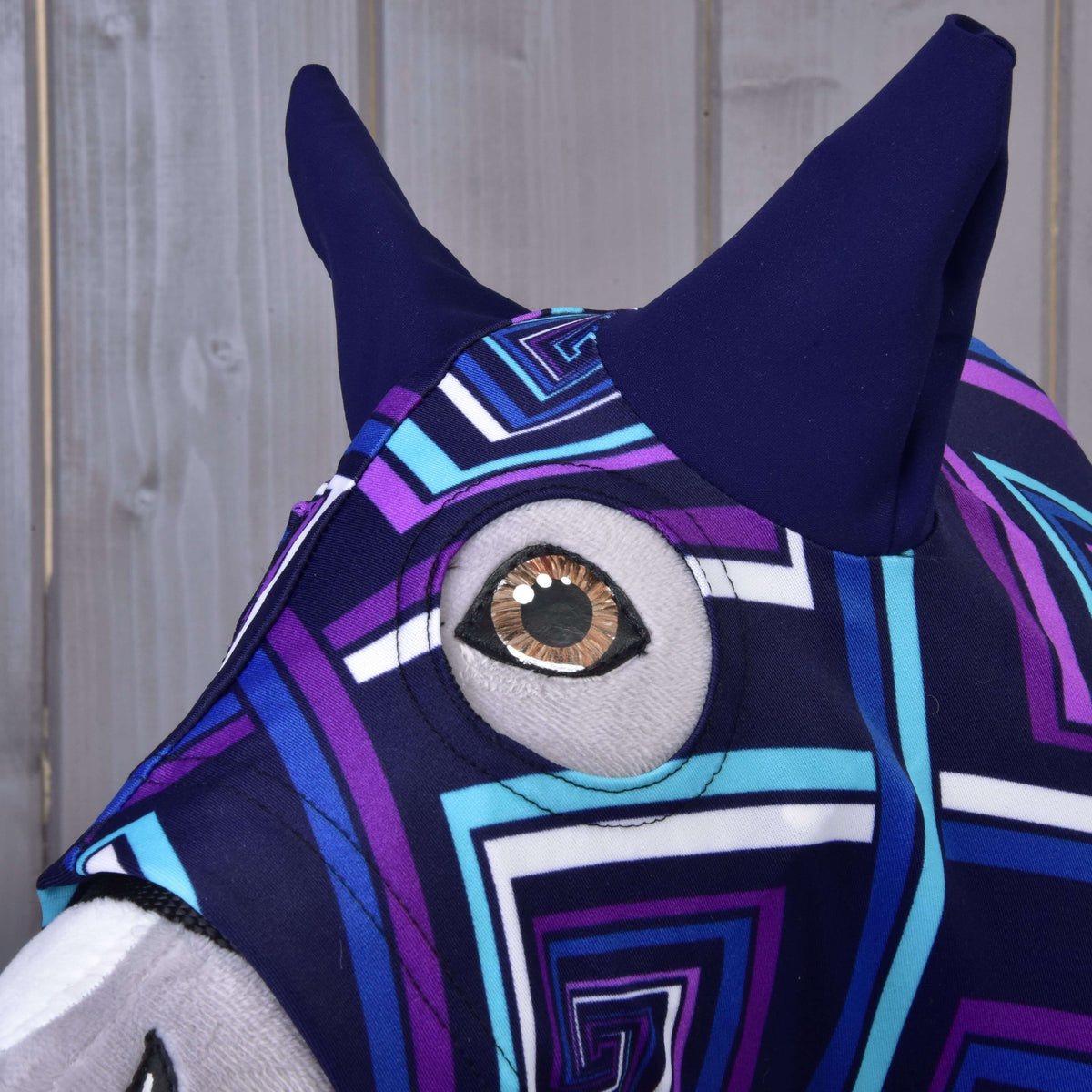 Közeli kép a kék Hobby Horse védőruháról (Lycra): sötétkék fülek és kerek szemnyílás a barna szem körül