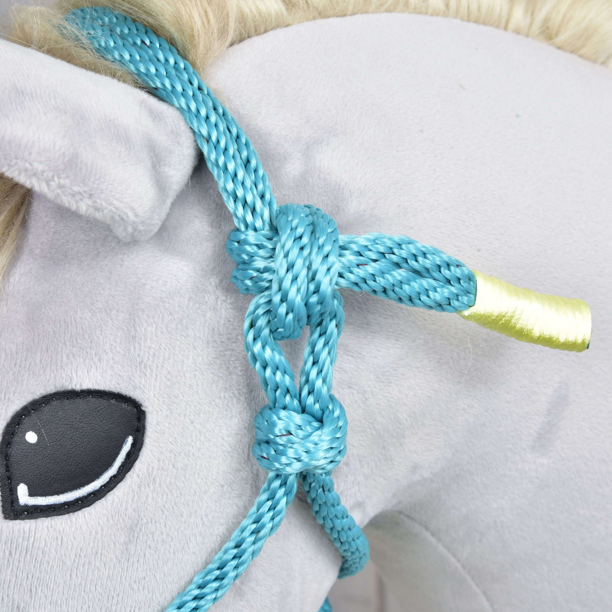 Close-up of the turquoise rope halter's knots below the ear and the rope end wrapped in pale yellow