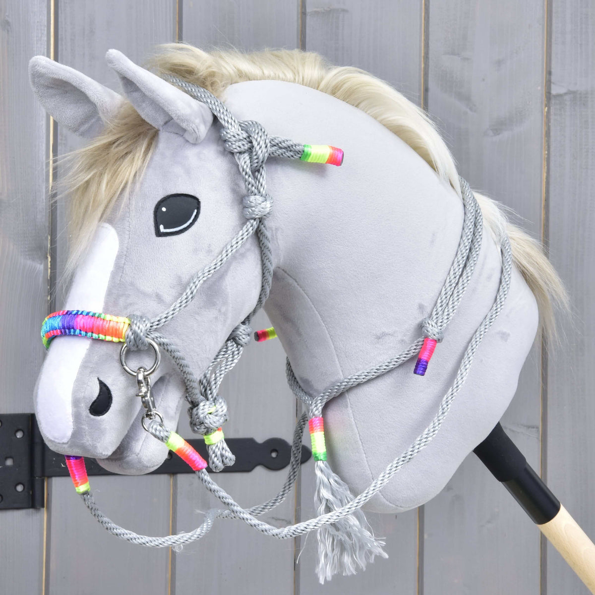 Szürke Hobby Horse ló a Manhattan kötélszettben: szürke csomózott kötőfék szivárványos orrszíjjal, kantárszár és bojtos nyakgyűrű