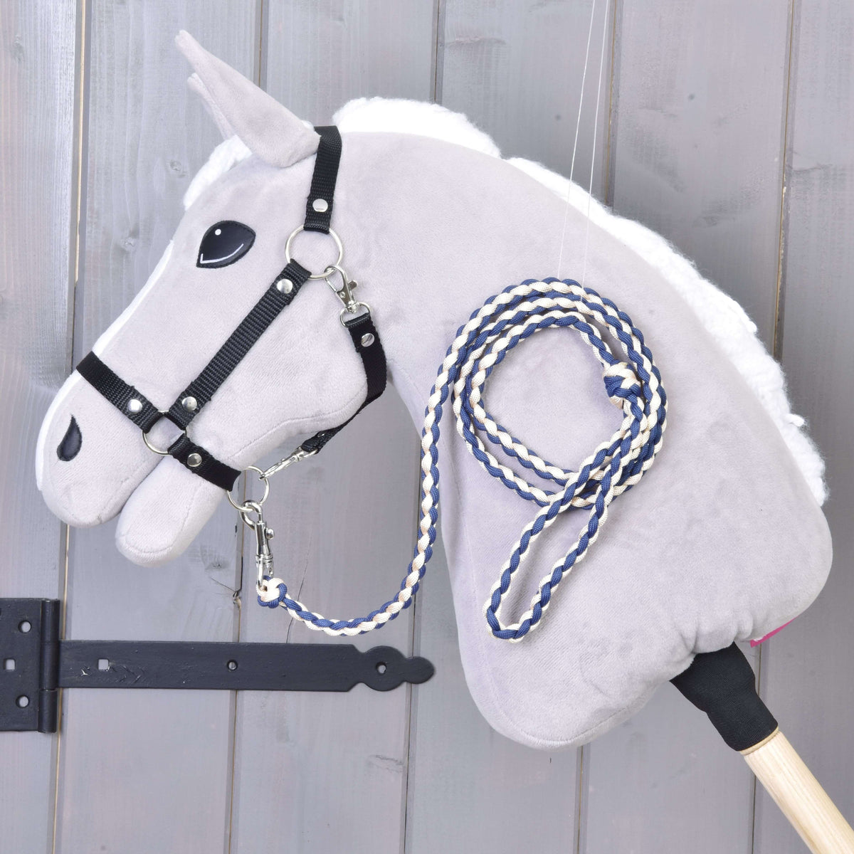 Sötétkék-krémszínű fonott vezetőszár egy fehér sörényű szürke Hobby Horse ló fekete kötőfékére csatolva