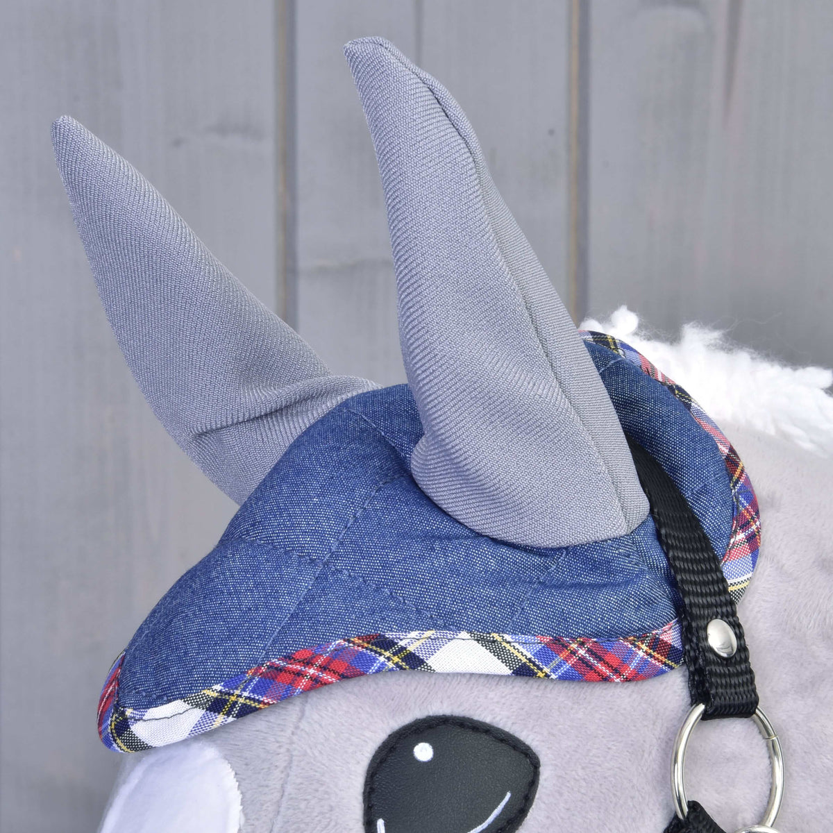 Close-up of the denim ear bonnet from Set Jeans with grey ears and red, blue and white tartan trim on a grey Hobby Horse