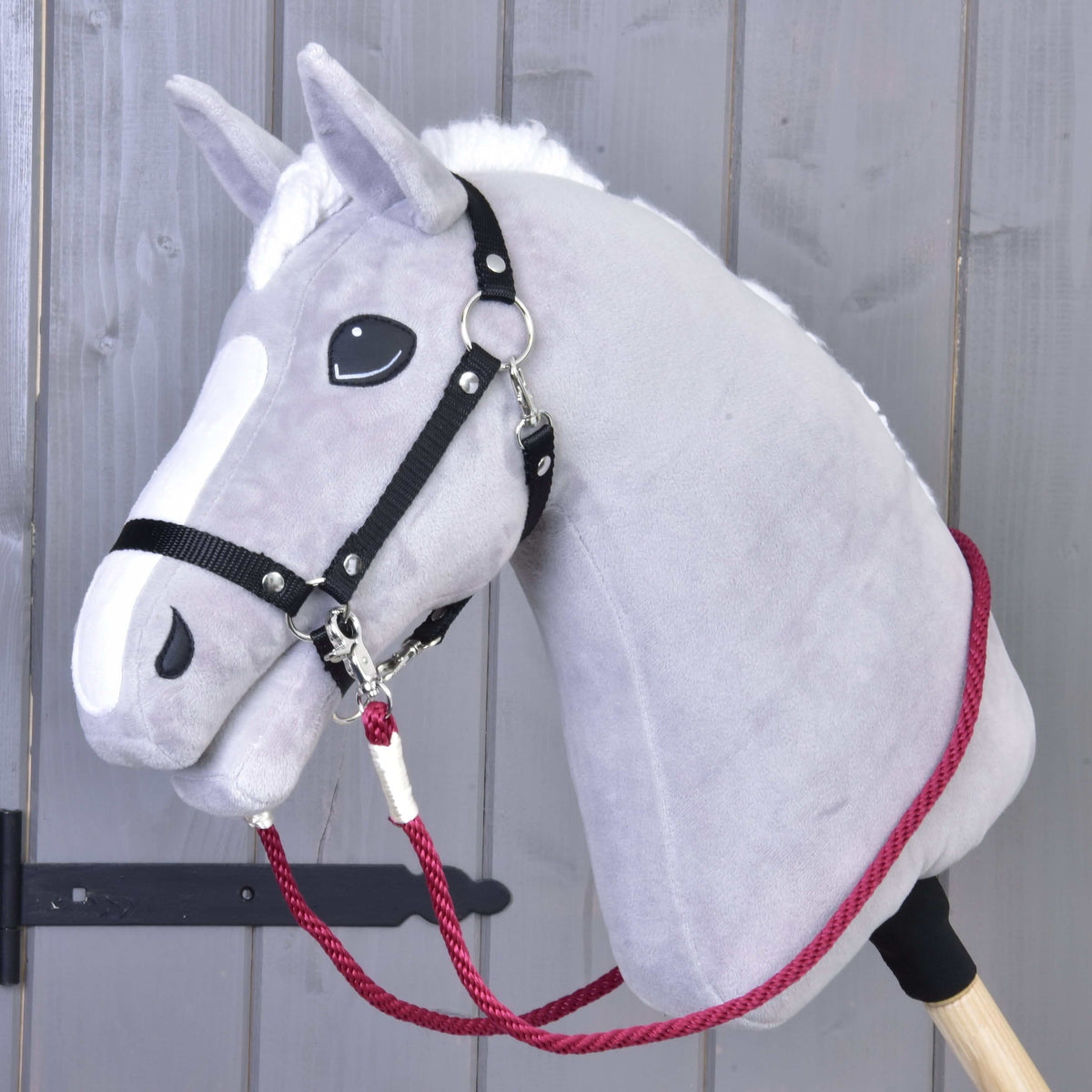 Grey plush Hobby Horse with a black halter and burgundy Czi-czi rope reins clipped under the chin
