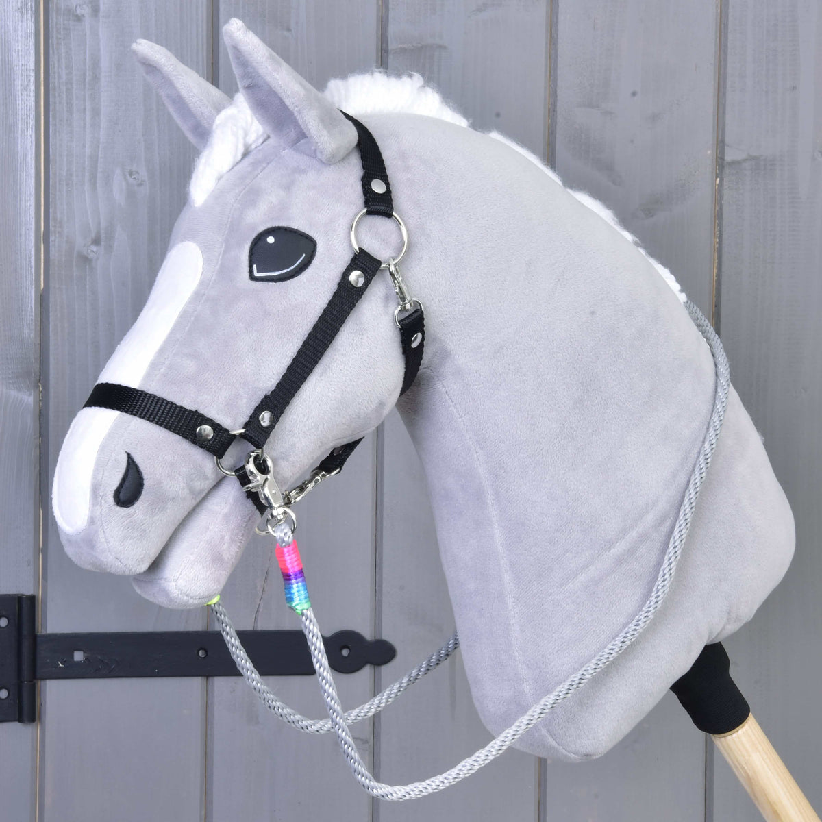 Szürke plüss Hobby Horse ló fekete kötőfékkel és szürke Manhattan kötél kantárszárral, a csatlakozásnál szivárványszínű tekeréssel