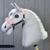 Szürke plüss Hobby Horse ló fehér hókával és fonott sörénnyel, rajta a fekete műbőr kötőfék fáradt rózsaszín szőrmével