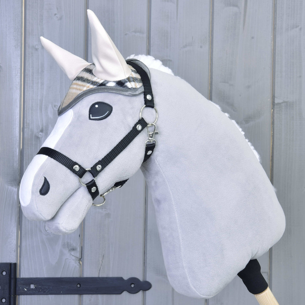 Light grey Hobby Horse in a black halter wearing the beige check ear bonnet with cream ear covers