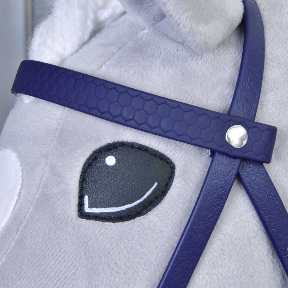 A sötétlila méhsejtmintás homlokszíj közelről ezüst szegeccsel egy szürke Hobby Horse ló mosolygó szeme mellett