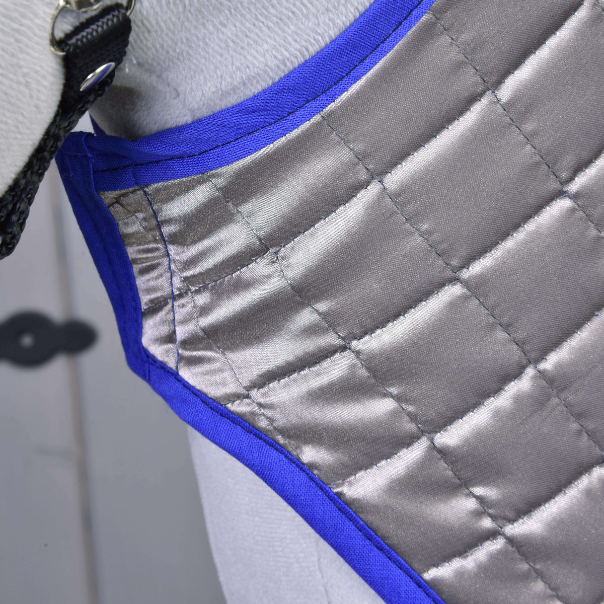 Közeli kép: a kifordítható DeLuxe Blue takaró ezüstszürke steppelt oldala királykék szegéllyel egy szürke Hobby Horse lovon