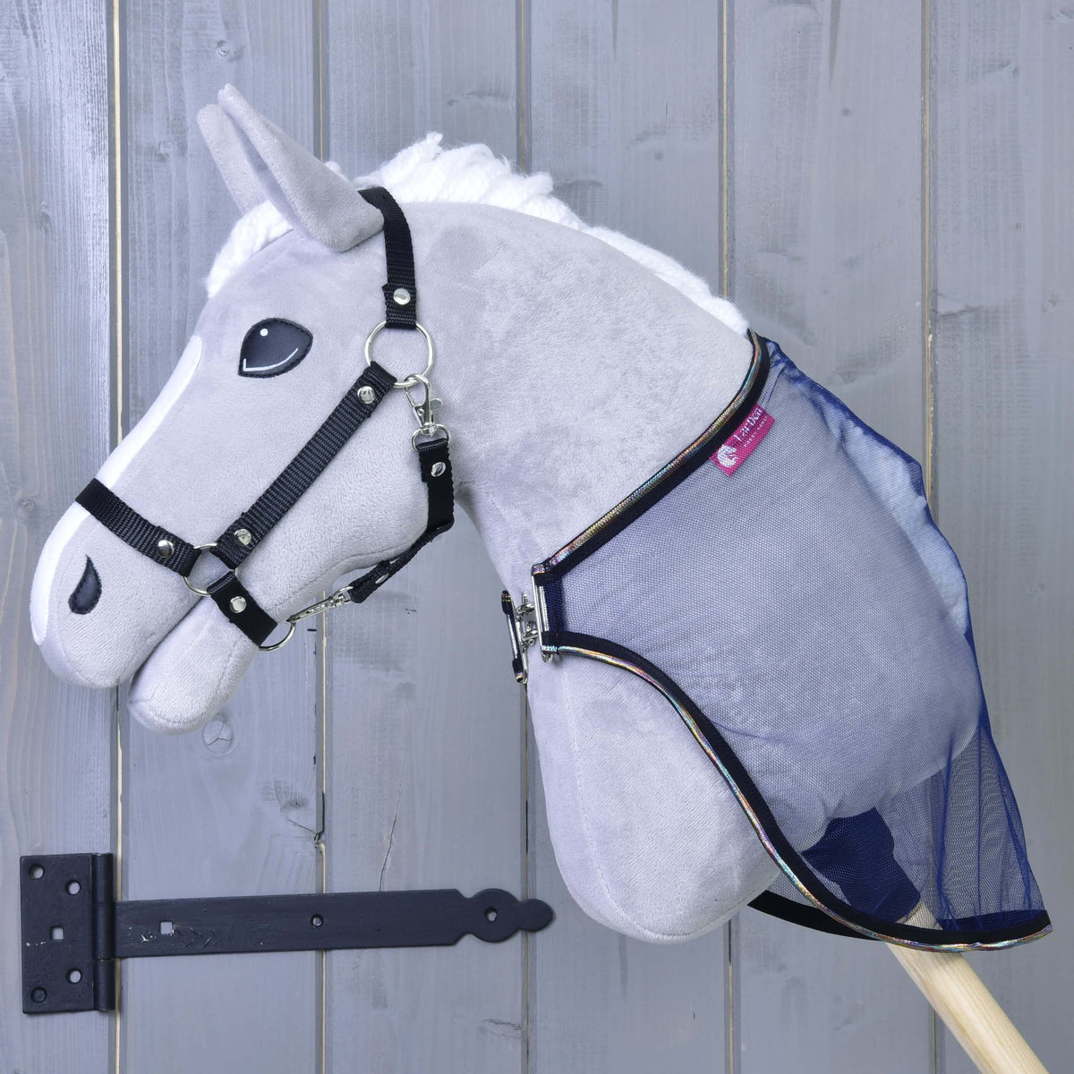 Grey Hobby Horse in a black halter wearing the sheer navy mesh fly sheet, fastened at the chest with a silver clip