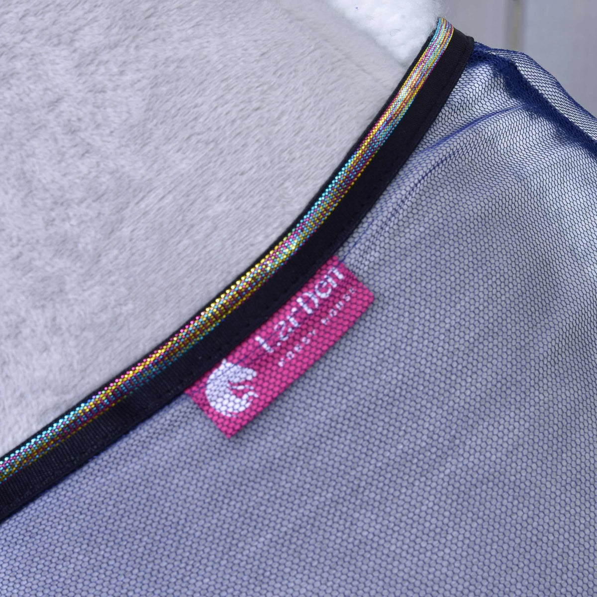 Close-up of the pink LarDen label and the black binding with metallic rainbow piping on the navy mesh