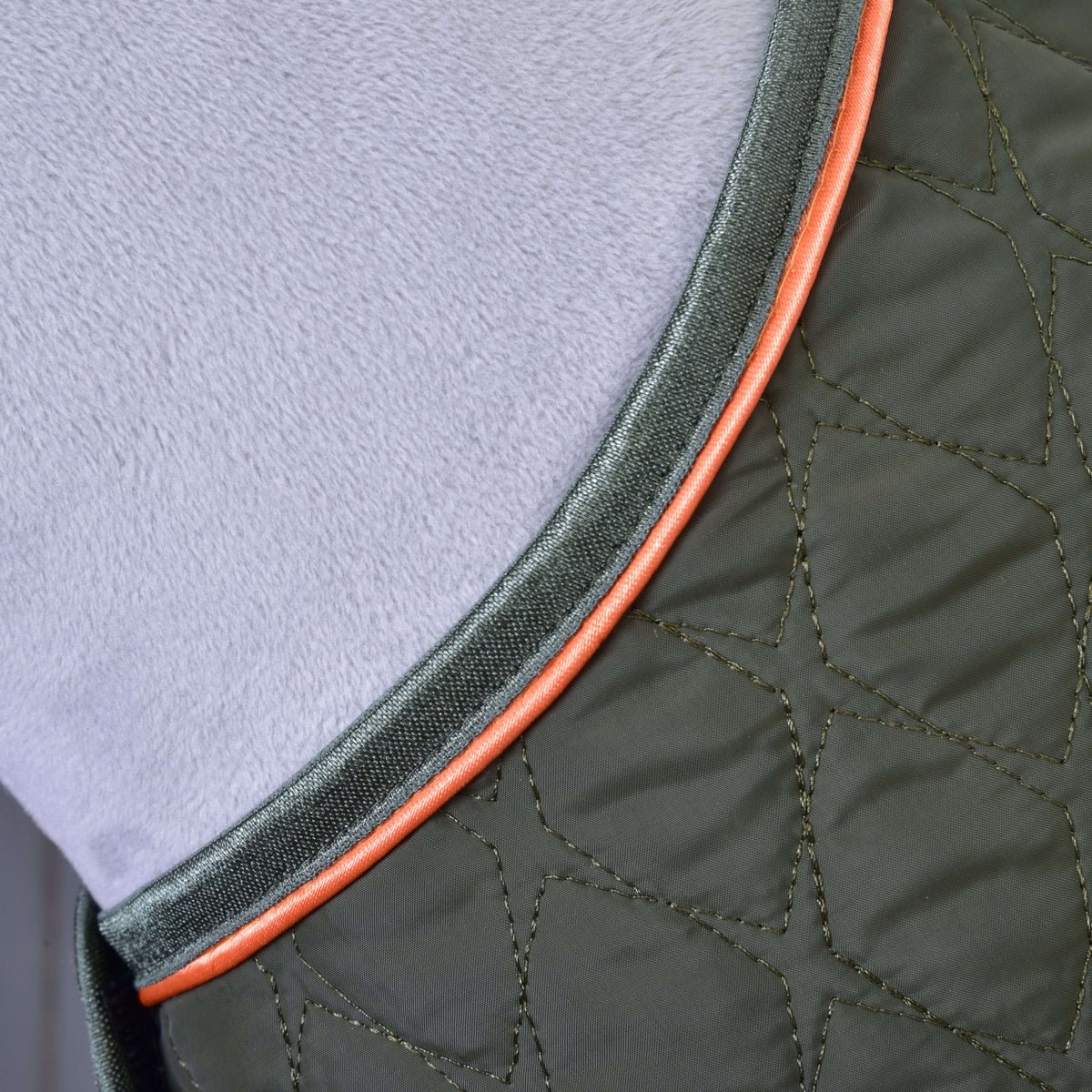 Close-up of the olive green quilting with dark green binding and orange piping on a grey Hobby Horse neck